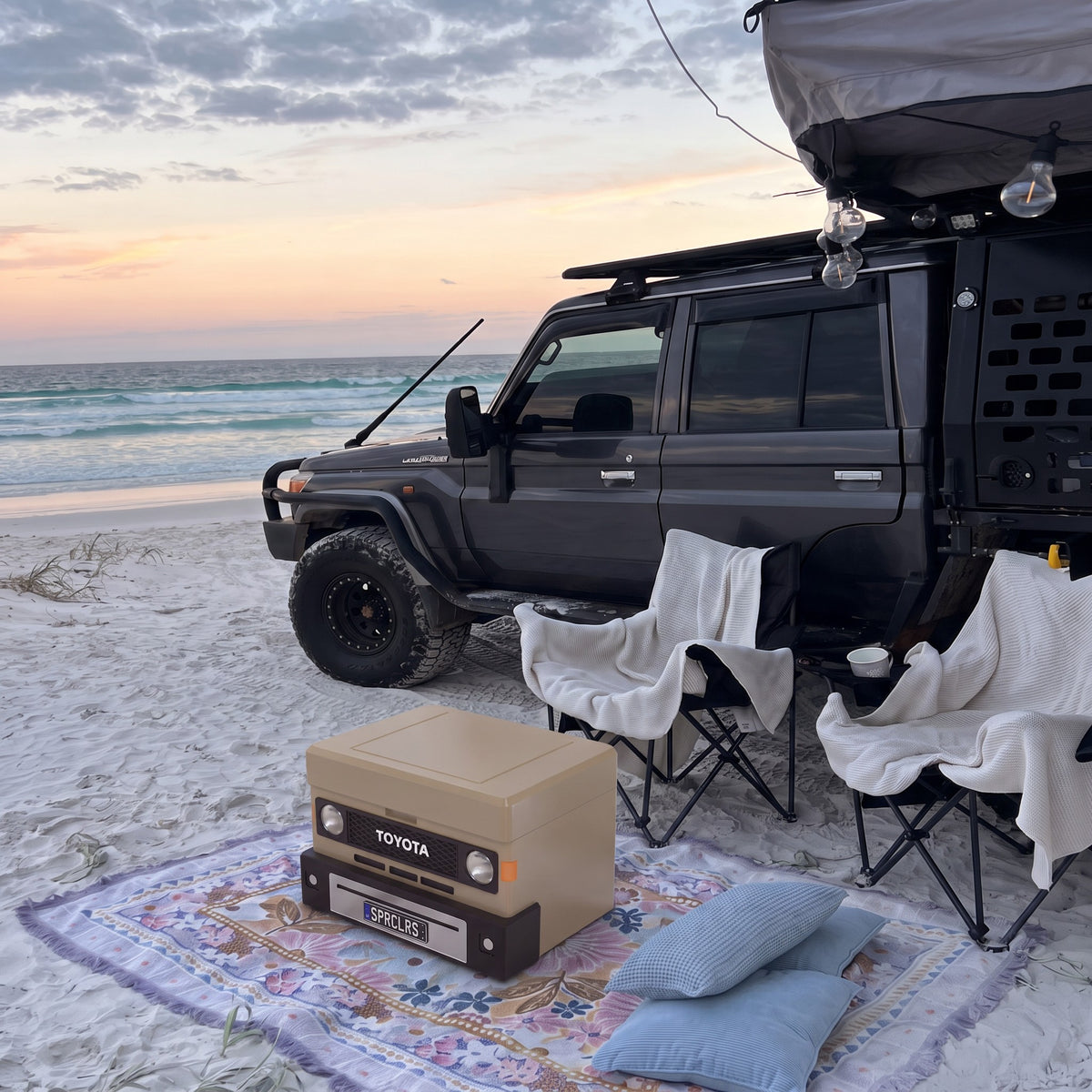 Sandy Taupe ute mini cooler on a beach rug in front of camp chairs and a 70 Series